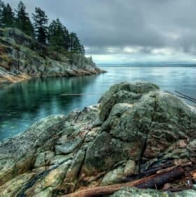 Scenic coastal view with rocky shoreline and forested cliffs in Kitimat, BC.