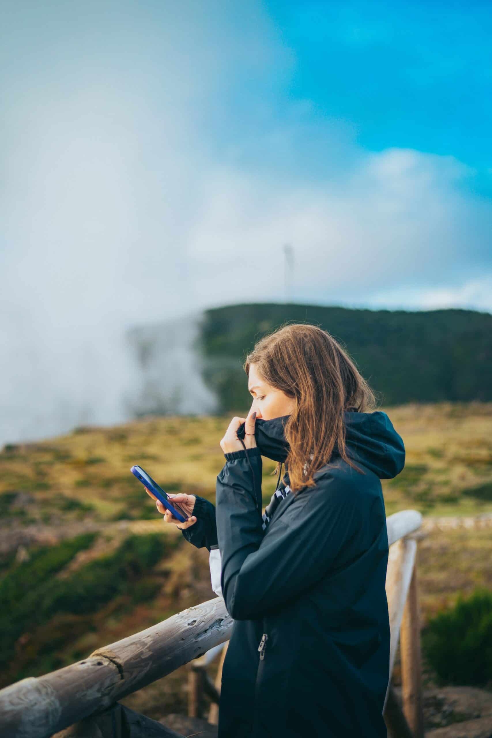Young woman checking air quality data on her phone at geothermal site.